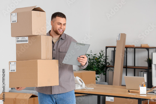 Male seller with parcels and clipboard in warehouse store