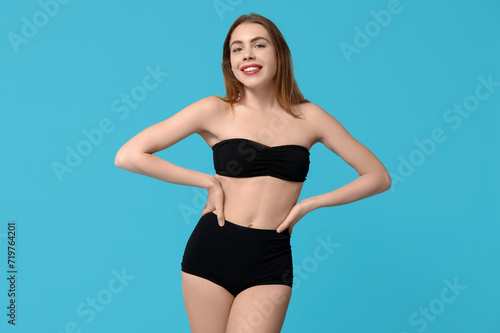 Beautiful young woman in black underwear on blue background