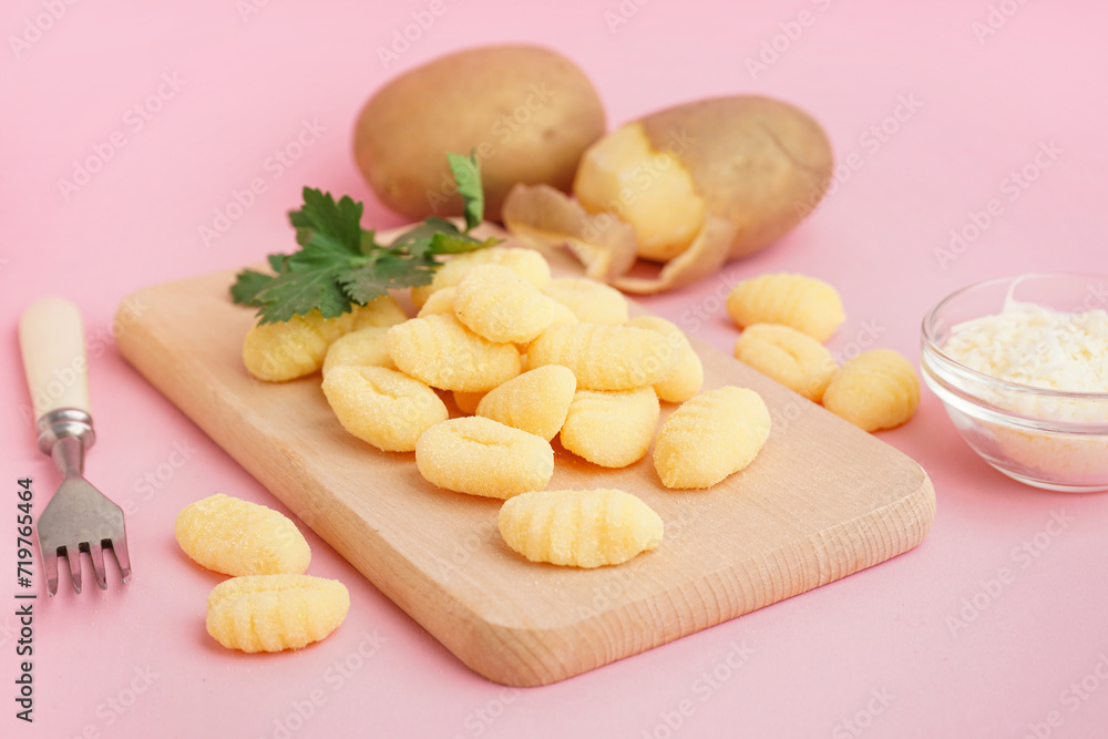 Wooden board with tasty gnocchi, grated cheese and parsley on pink background, closeup Wooden board with tasty gnocchi, grated cheese and parsley on pink background, closeup