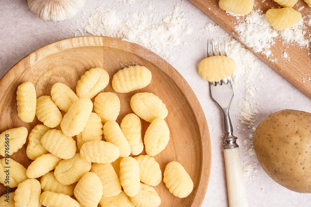 Wooden plate with tasty gnocchi and fork on light background Wooden plate with tasty gnocchi and fork on light background