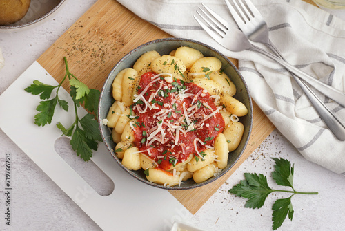 Bowl of tasty gnocchi with tomato sauce and cheese on white background photo