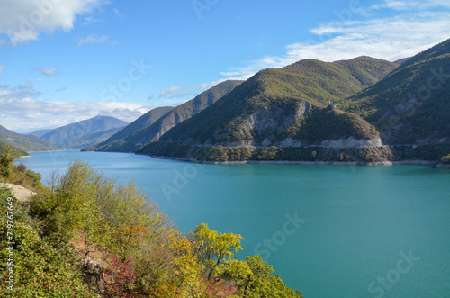 Turquoise water surface of the Zhinvali reservoir surrounded by dense green mountains on a sunny day. Picturesque landscapes of Georgia