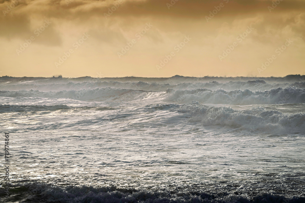 stormy waves at sunset, yellow sky at beach stormy waves at sunset, yellow sky at beach