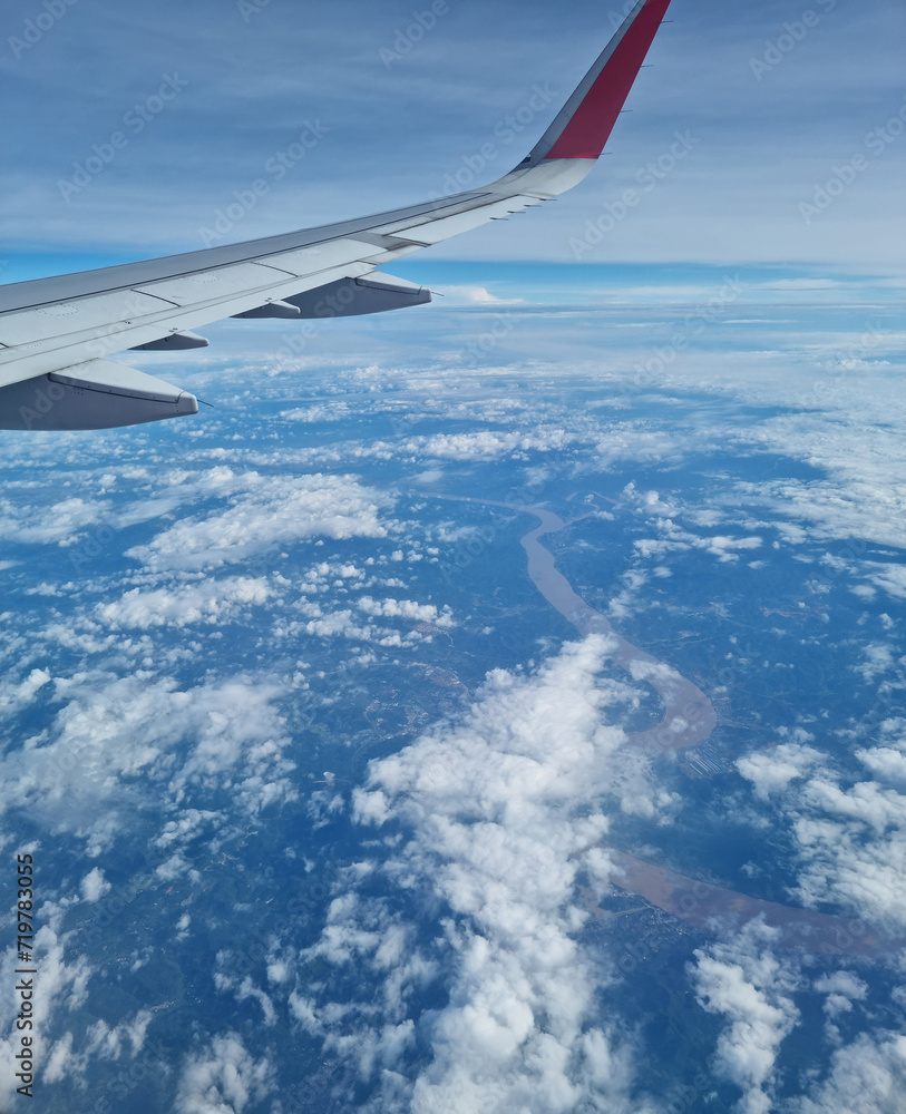 Airplane wing through the clouds in the sky.