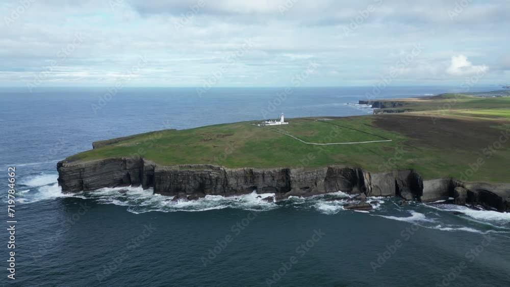 Serene coastline with a lighthouse, cliffs, and waves crashing at Loop Head. From Aerial perspective Serene coastline with a lighthouse, cliffs, and waves crashing at Loop Head. From Aerial perspective