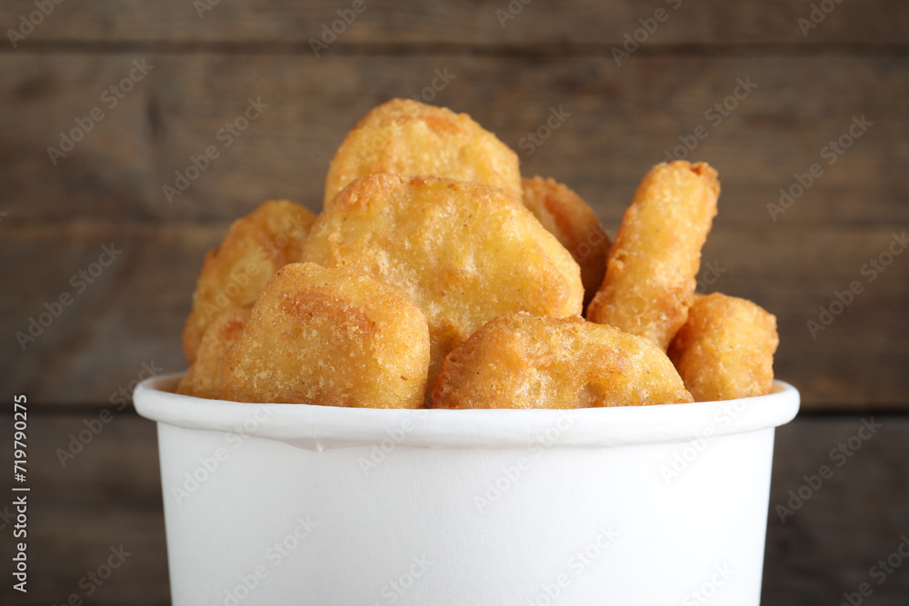 Bucket with tasty chicken nuggets on wooden background, closeup Bucket with tasty chicken nuggets on wooden background, closeup