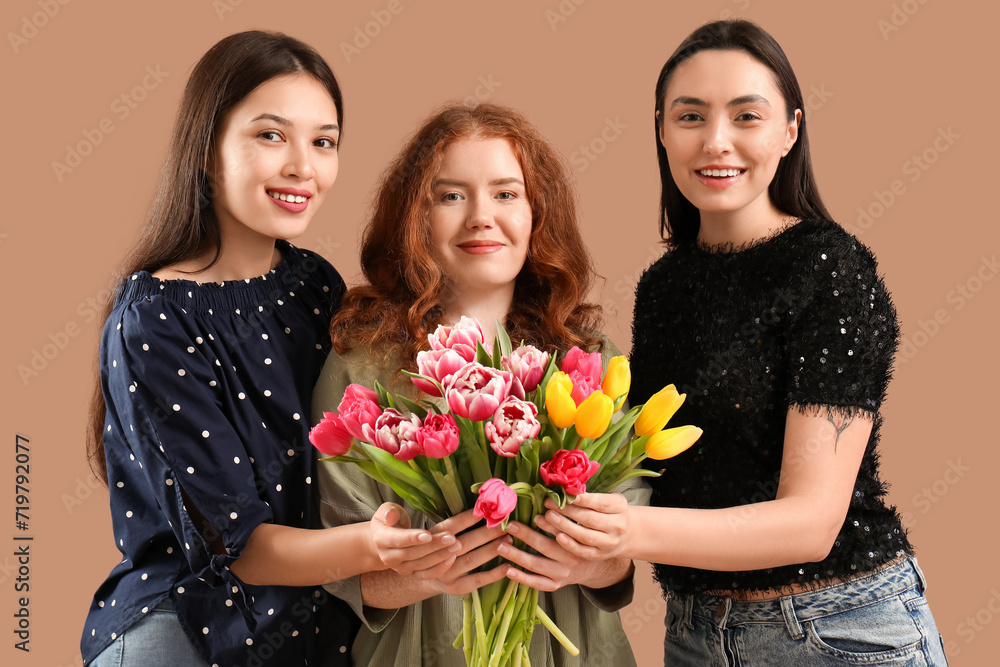 Young women with bouquet of beautiful tulips on brown background. International Women's Day Young women with bouquet of beautiful tulips on brown background. International Women's Day