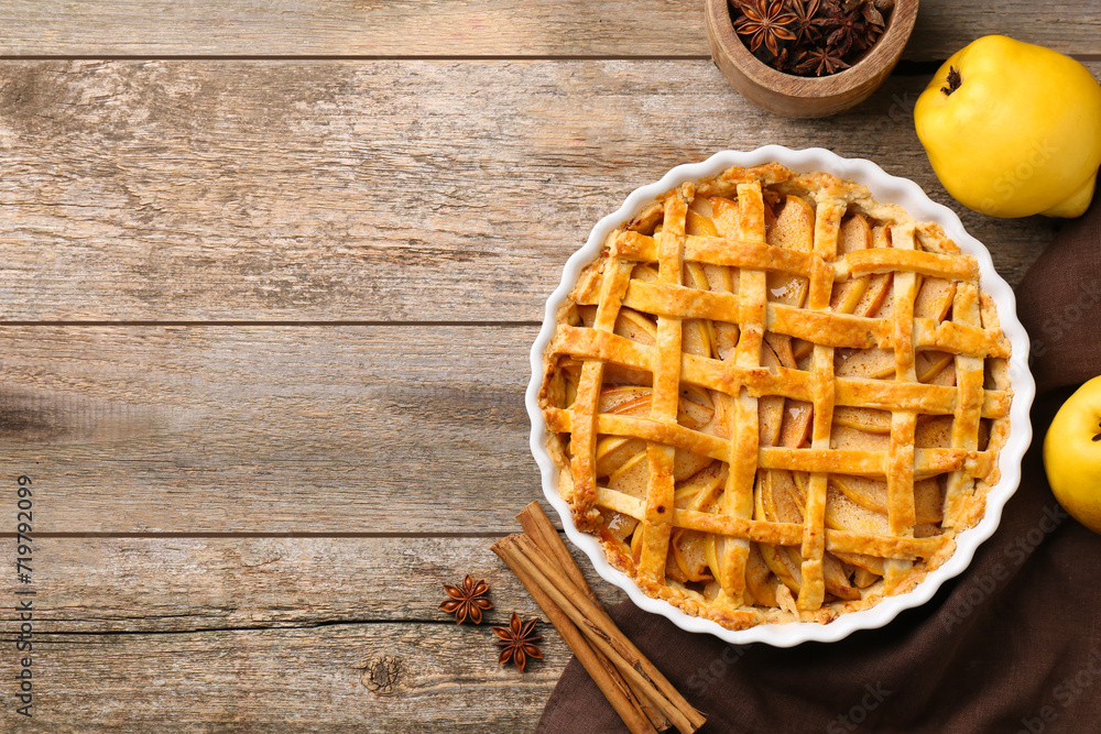 Tasty homemade quince pie with fresh fruits and spices on wooden table, flat lay. Space for text Tasty homemade quince pie with fresh fruits and spices on wooden table, flat lay. Space for text