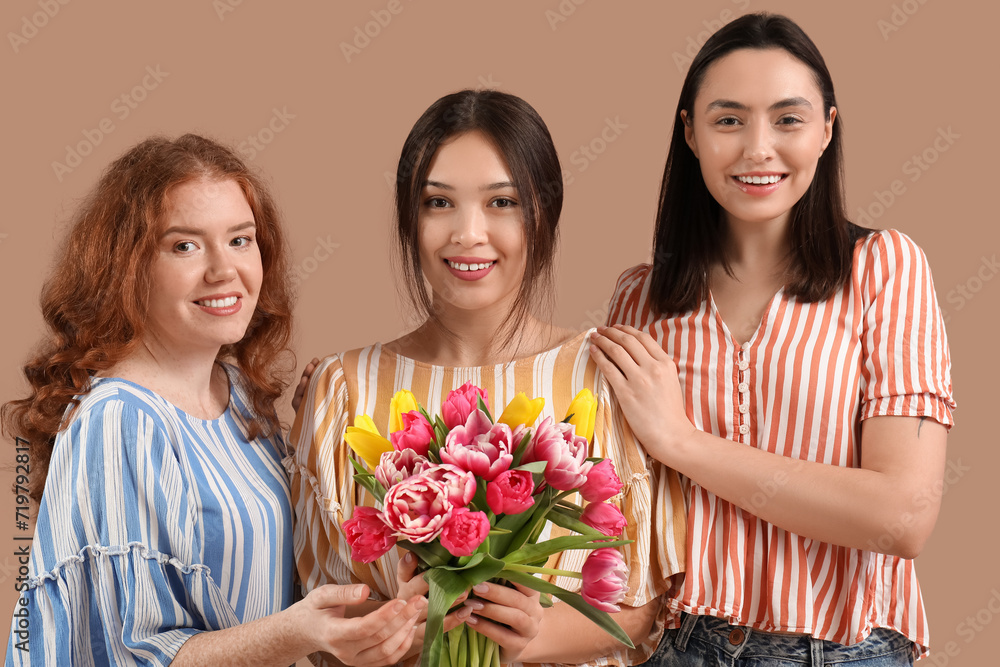 Young women with bouquet of beautiful tulips on brown background. International Women's Day Young women with bouquet of beautiful tulips on brown background. International Women's Day