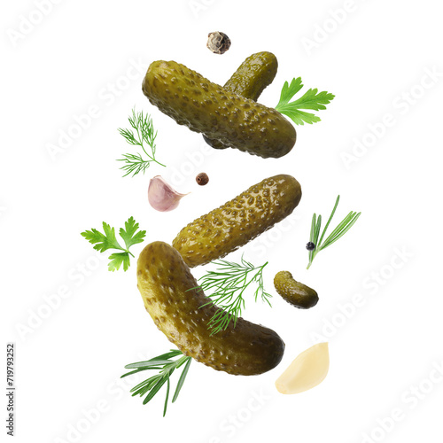 Tasty pickled cucumbers, herbs and spices falling on white background photo