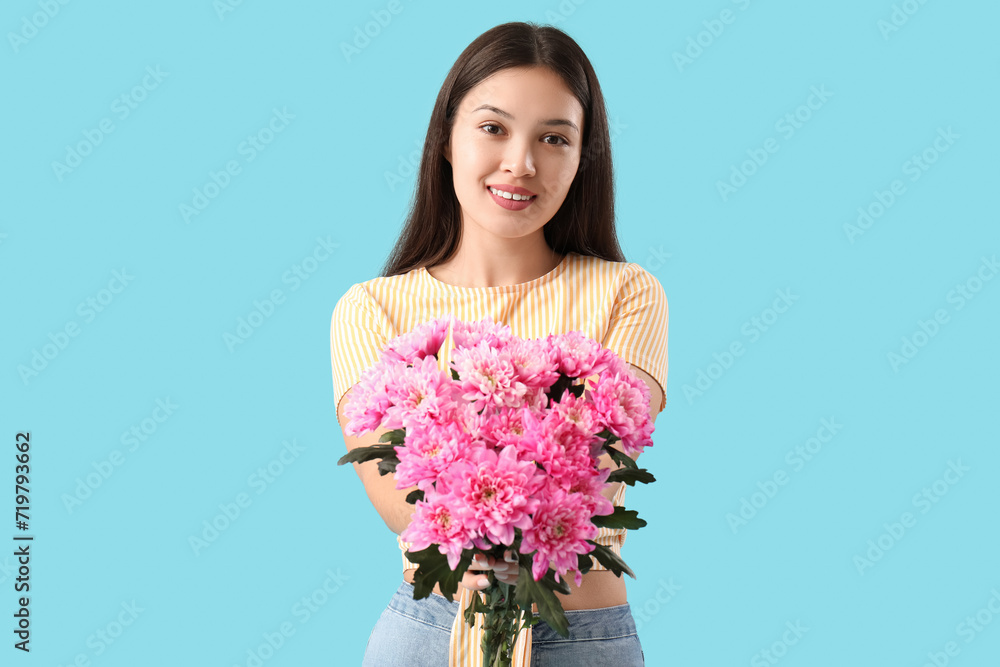 Beautiful young Asian woman with bouquet of pink chrysanthemum flowers on blue background. International Women's Day Beautiful young Asian woman with bouquet of pink chrysanthemum flowers on blue background. International Women's Day