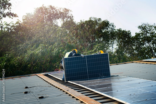 Worker Technicians are working to construct solar panels system on roof. Installing solar photovoltaic panel system. Men technicians carrying photovoltaic solar modules on roof.