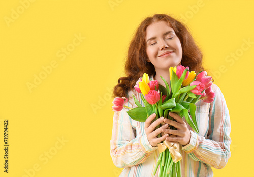 Young woman with bouquet of beautiful tulips on yellow background. International Women's Day