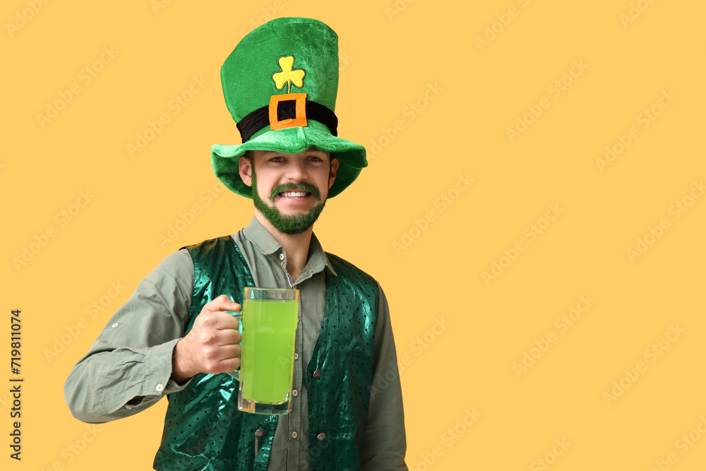 Happy young man in leprechaun hat with green beard holding glass of beer on yellow background. St. Patrick's Day celebration Happy young man in leprechaun hat with green beard holding glass of beer on yellow background. St. Patrick's Day celebration