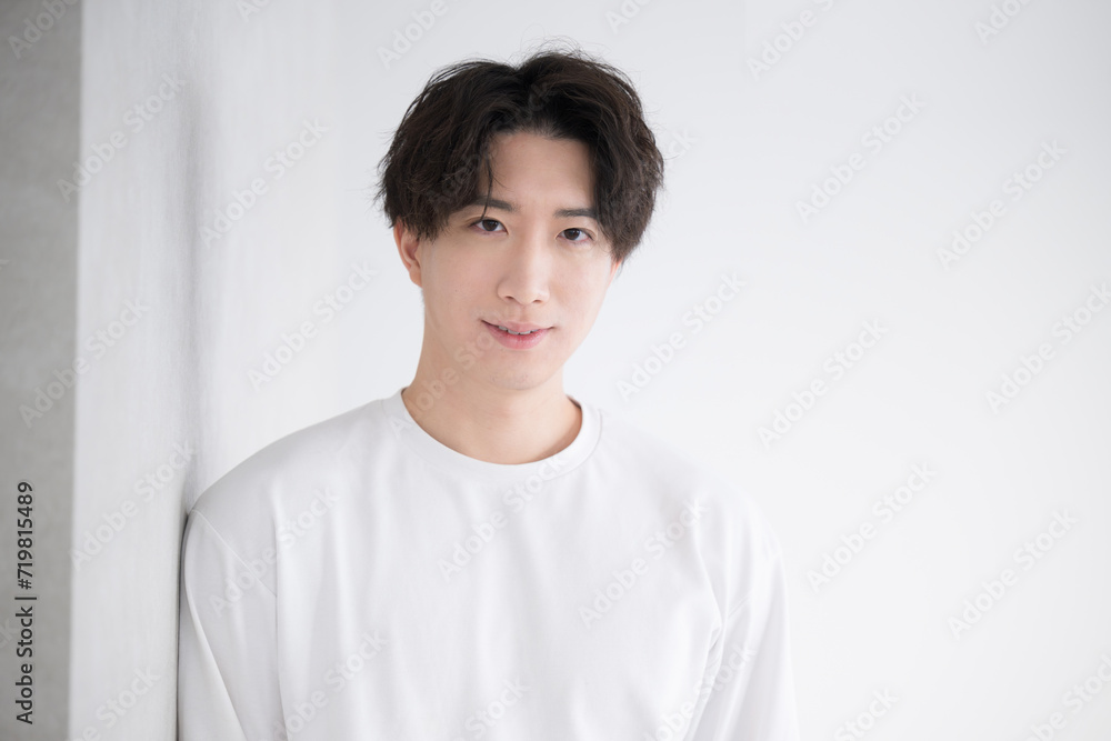 Handsome Asian man leaning against a wall, smiling and laughing Handsome Asian man leaning against a wall, smiling and laughing