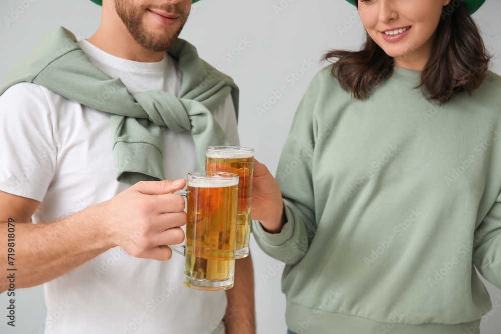 Beautiful young couple with glasses of beer on grey background. St. Patrick's Day celebration Beautiful young couple with glasses of beer on grey background. St. Patrick's Day celebration