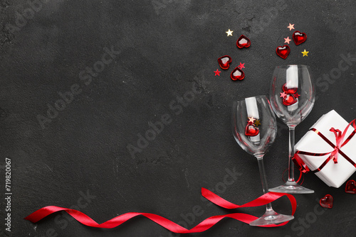 Composition with gift box, glasses and hearts for Valentine's Day celebration on dark background