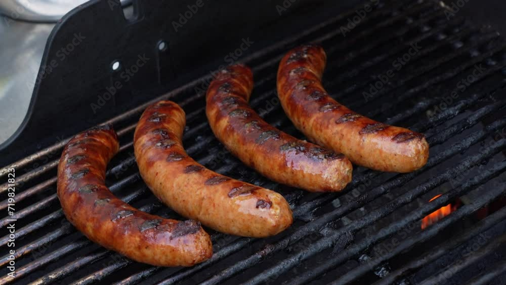 Grilled BBQ meat sausages on stainless grill with fire flames close up. Food and cuisine concept. Grilled BBQ meat sausages on stainless grill with fire flames close up. Food and cuisine concept.