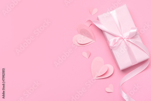 Composition with gift box and paper hearts for Valentine's Day celebration on pink background