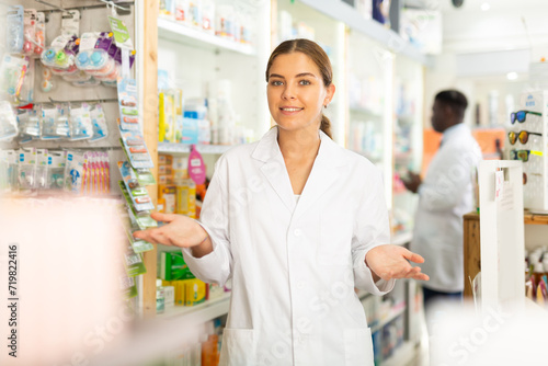 Portrait of a positive young female pharmacist in a pharmacy, standing in the trading floor. Close-up portrait