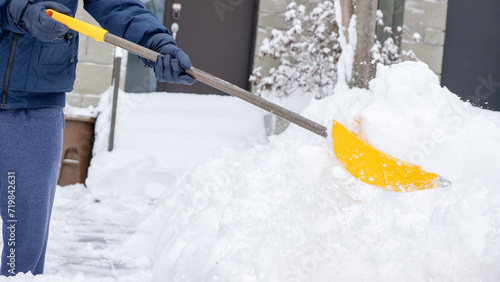 Man shoveling snow off of his driveway after a winter storm in Canada. Man with snow shovel cleans sidewalks in winter. Winter time.