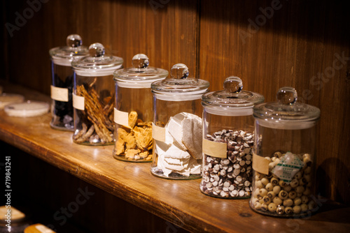 Chinese medicinal herbs in the glass jars on a wooden shelf photo