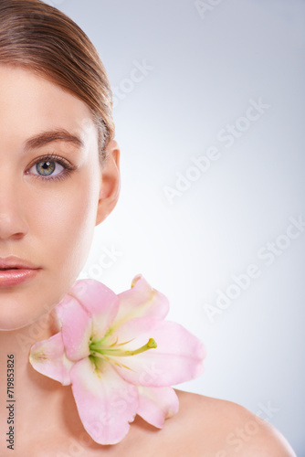 Half face  woman and dermatology with flowers  beauty and wellness on white studio background. Closeup  portrait or model with natural cosmetics or grooming with shine or glow with skincare or smooth