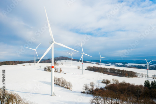 Panoramic view of wind turbines farm in the field in winter. Electricity production from clean and renewable energy with copy space.