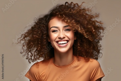 Portrait of beautiful young woman with curly hair on grey background