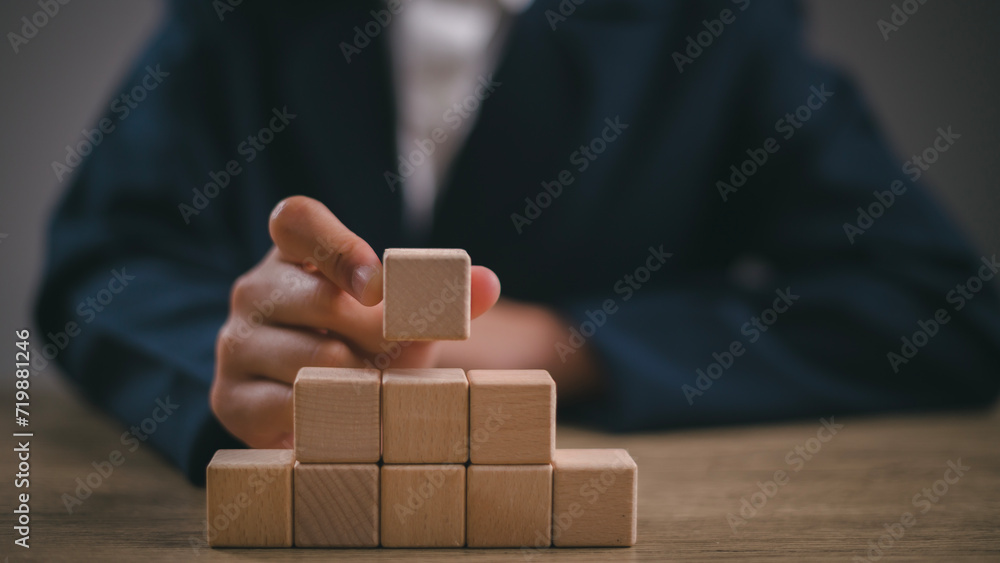 Businesswomen stack blank wooden cubes on the table with copy space, empty wooden cubes for input wording, and an infographic icon.
