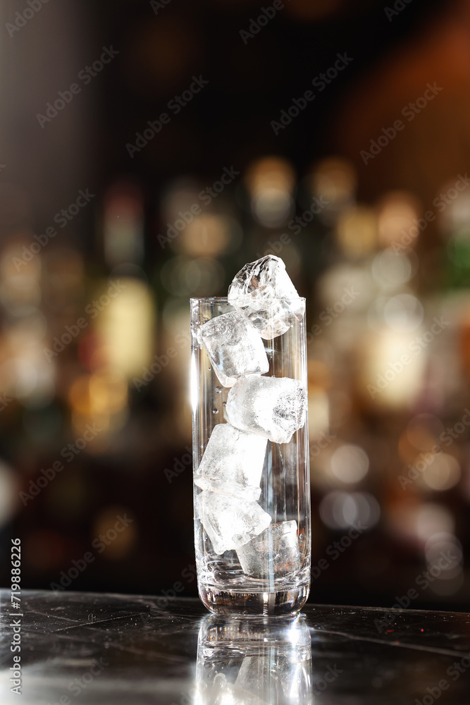 Whiskey and other long alcohol drinks glass filled with a lot of ice cubes and prepared to pour the drink. Cocktails and drinking in a pub. Empty glass.