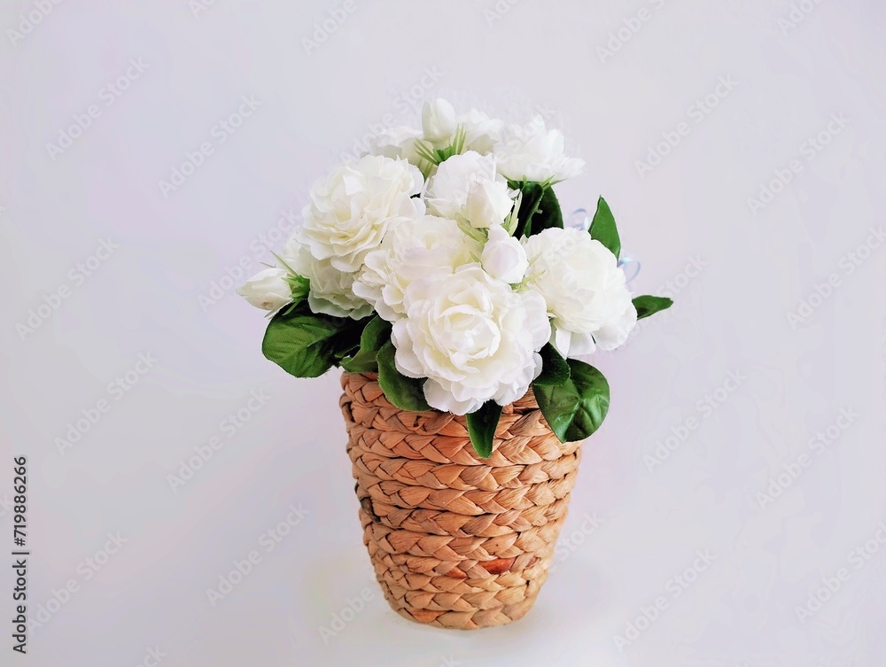 Pictured are white plastic flowers with green leaves called jasmine flowers in a brown basket. They are fragrant and are used as a symbol of Mother's Day in Thailand. Pictured are white plastic flowers with green leaves called jasmine flowers in a brown basket. They are fragrant and are used as a symbol of Mother's Day in Thailand.