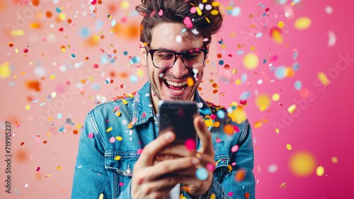 Happy young man using his smart phone with confetti photo