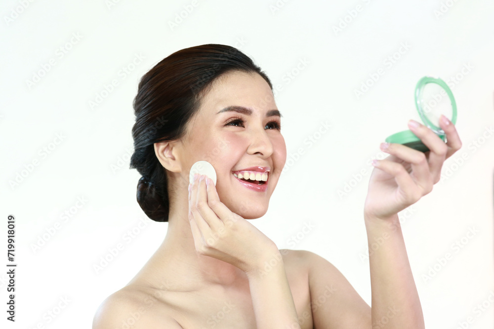 Personable beautiful natural soft makeup woman using powder puff for facial makeup Cushion foundation applied on young woman's face in an isolated background. Personable beautiful natural soft makeup woman using powder puff for facial makeup Cushion foundation applied on young woman's face in an isolated background.