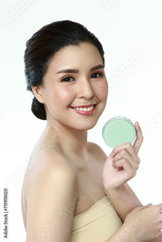 Personable beautiful natural soft makeup woman using powder puff for facial makeup Cushion foundation applied on young woman's face in an isolated background.