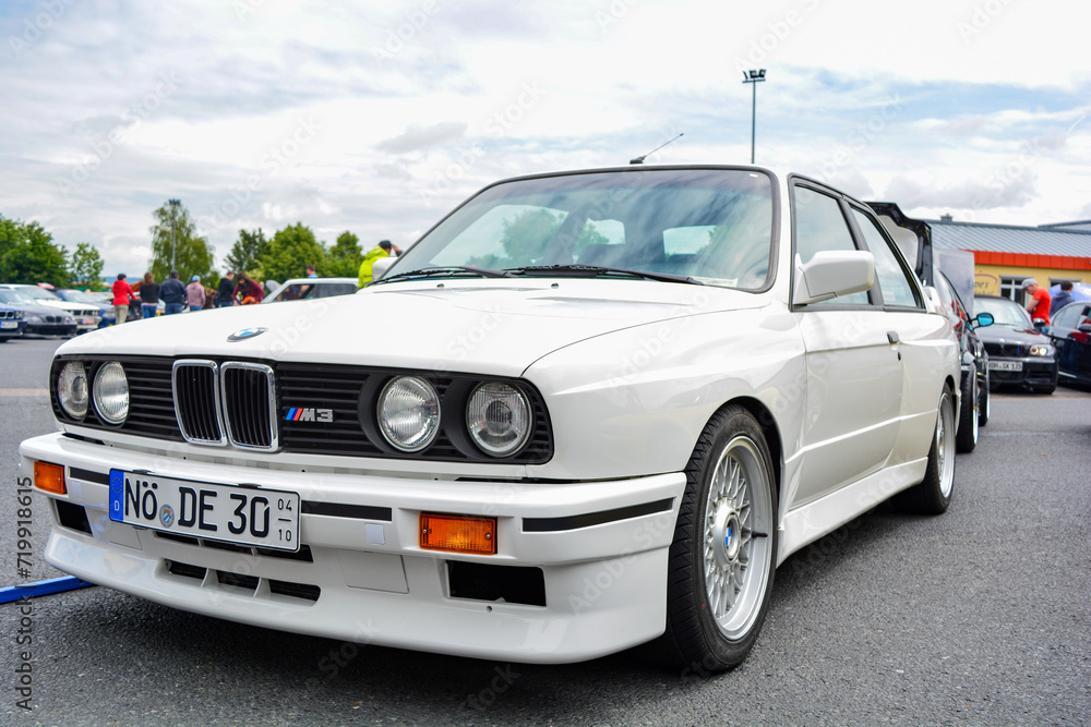 Front of a white BMW e30 M3 vintage car with headlights, fenders ...