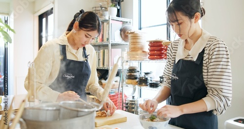 Cooking class, restaurant and women with Japanese food in a kitchen with chef and learning professional skill. Student, education and Asian cuisine course with people together working on skills photo