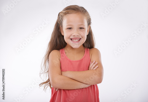 Child, smile and portrait or confidence with arms crossed in studio for good mood, happy or relax. Female person, girl model and face or white background as mockup space or proud, peace or positivity © Tasneem H/peopleimages.com