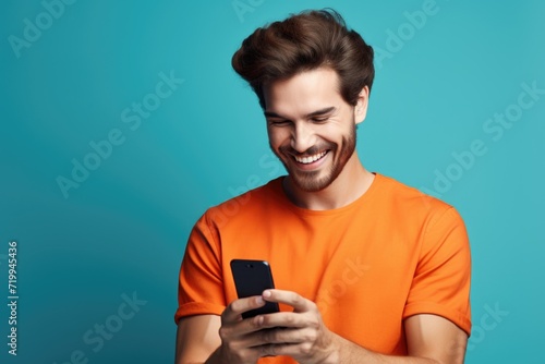 A man is pictured smiling as he looks at his cell phone. This image can be used to depict happiness, technology, communication, or social media