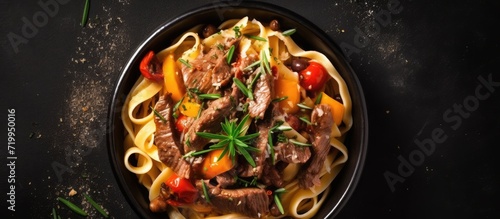 Top view Fettuccine pasta with beef in black bowl. Background Copy space