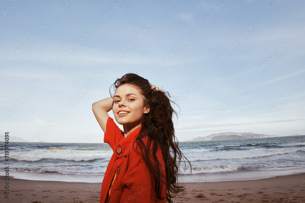 Smiling Woman Embracing Summer Joy, Relaxing on the Beach: Portrait of a Happy Young Lady in Red Clothes, Feeling Freedom and Enjoying Nature Smiling Woman Embracing Summer Joy, Relaxing on the Beach: Portrait of a Happy Young Lady in Red Clothes, Feeling Freedom and Enjoying Nature