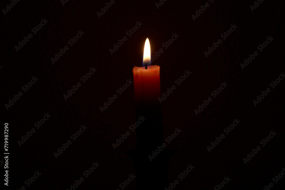 Fine red paraffin memorial candle burns on a black background close-up Fine red paraffin memorial candle burns on a black background close-up