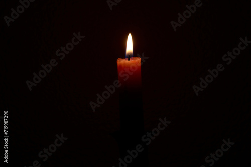 Fine red paraffin memorial candle burns on a black background close-up