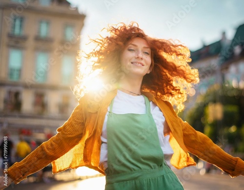Mujer caucásica y pelirroja, bailando en la calle en un atardecer con el sol a su espalda