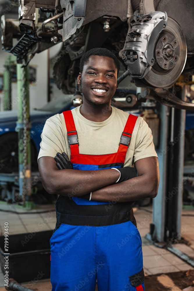 Fototapeta premium Portrait of young african man car service worker wearing uniform standing in garage