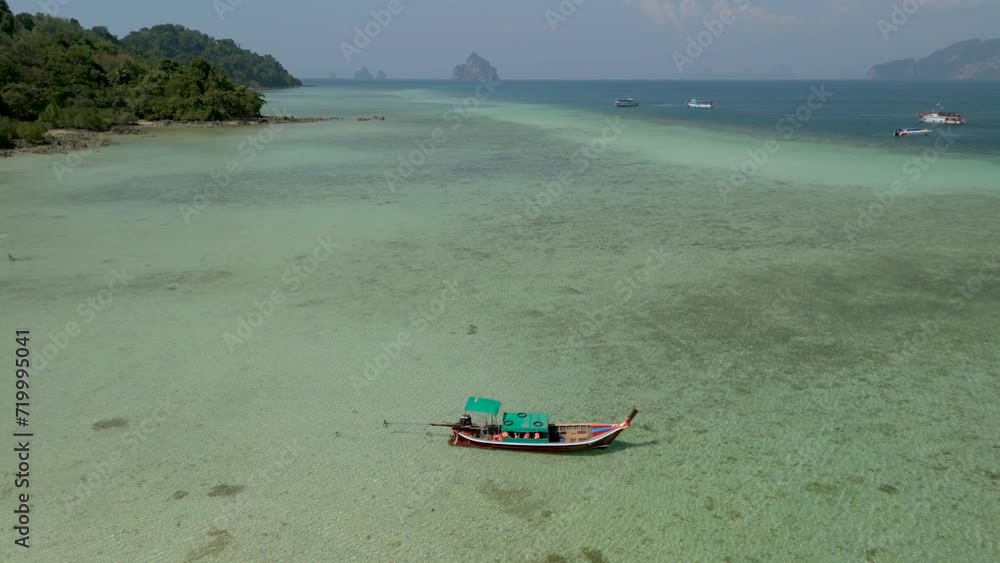 Drone aerial view at Koh Kradan tropical island with a a turqouse colored ocean, blue ocean with longtail boats at the beach of Koh Kradan Island