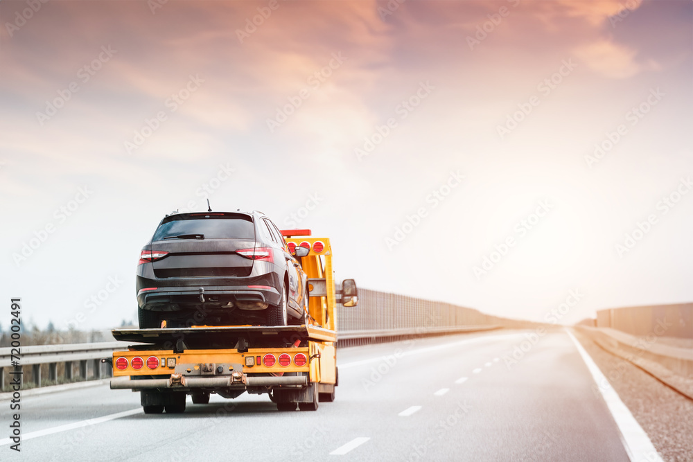 Tow truck at work. On an open road under the vast sky lies the silent tale of a car’s breakdown and the timely arrival of help.