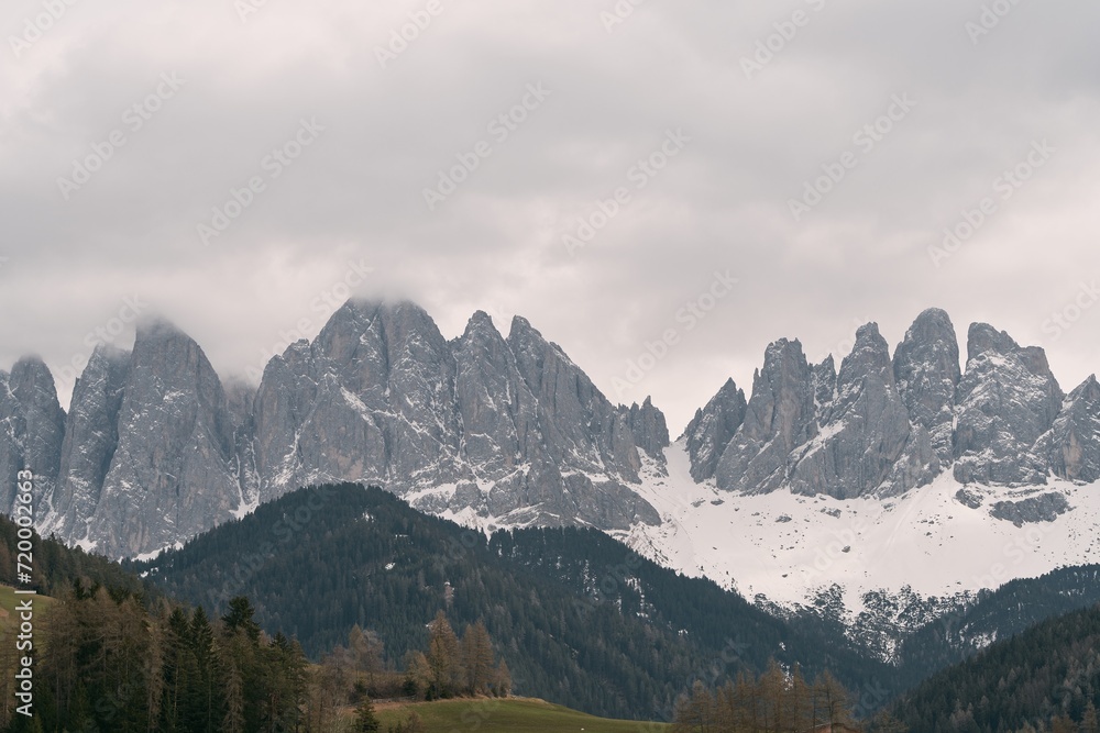 Majestic Dolomites covered with snow and ice in the sunset glow. Trekking and tourism natural background. Nature masterpiece with towering snow-capped peaks and a tranquil forest.