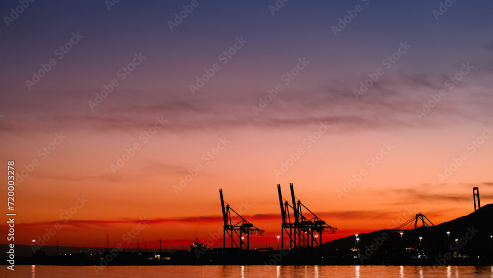 Sunset sky by the sea beach with silhouette harbour and blurry twilight Dusk sky in Evening in orange, red, purple, blue with cloud,Horizon Nature Golden Sky,Beautiful Sunrise background