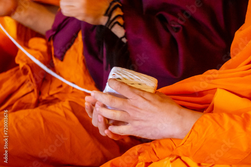 lose up monk's hand holding holy thread, buddhist holy day, thai buddhist monk ordination ceremony wallpaper background concept photo
